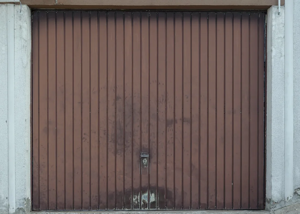 a closed brown steel garage door with vertical ribs