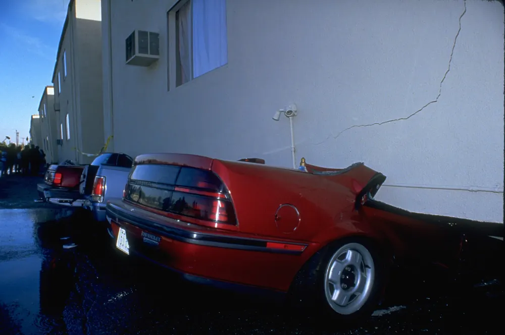 Cars crushed against the wall of a damaged apartment building after the 1994 earthquake