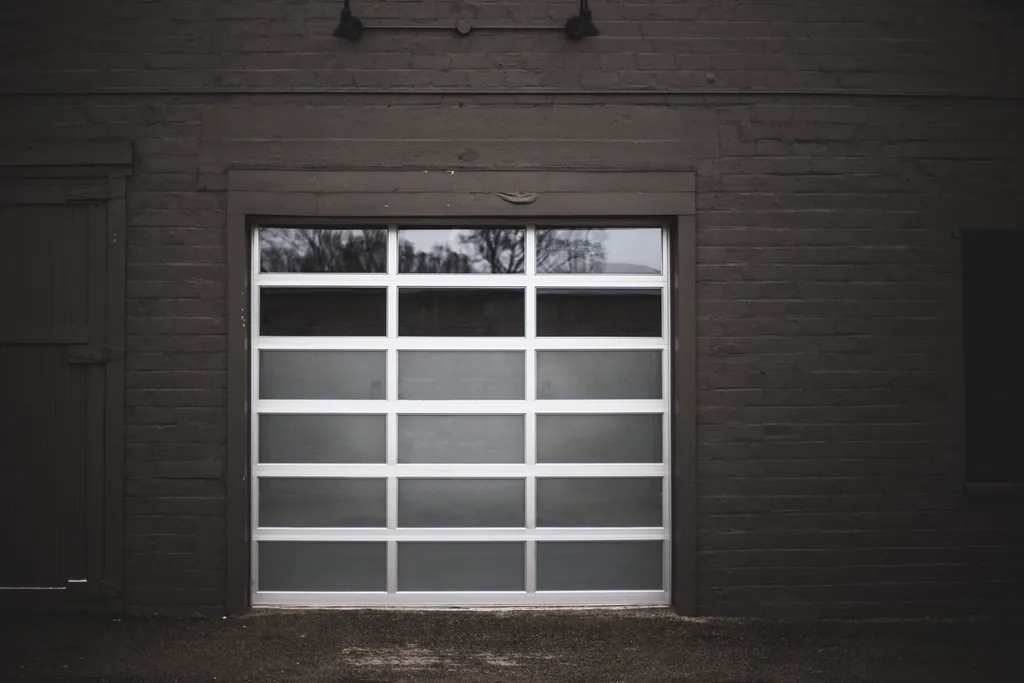 a modern glass-panel garage door in a dark wall