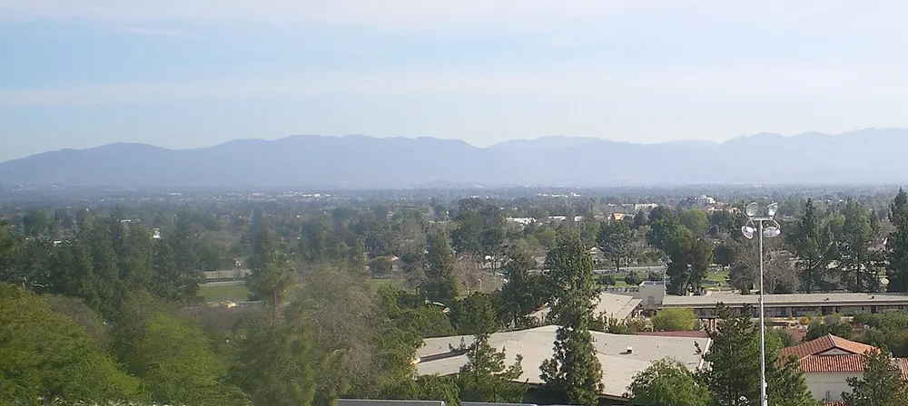 Rooftops and trees spreading across a valley toward a line of distant mountains